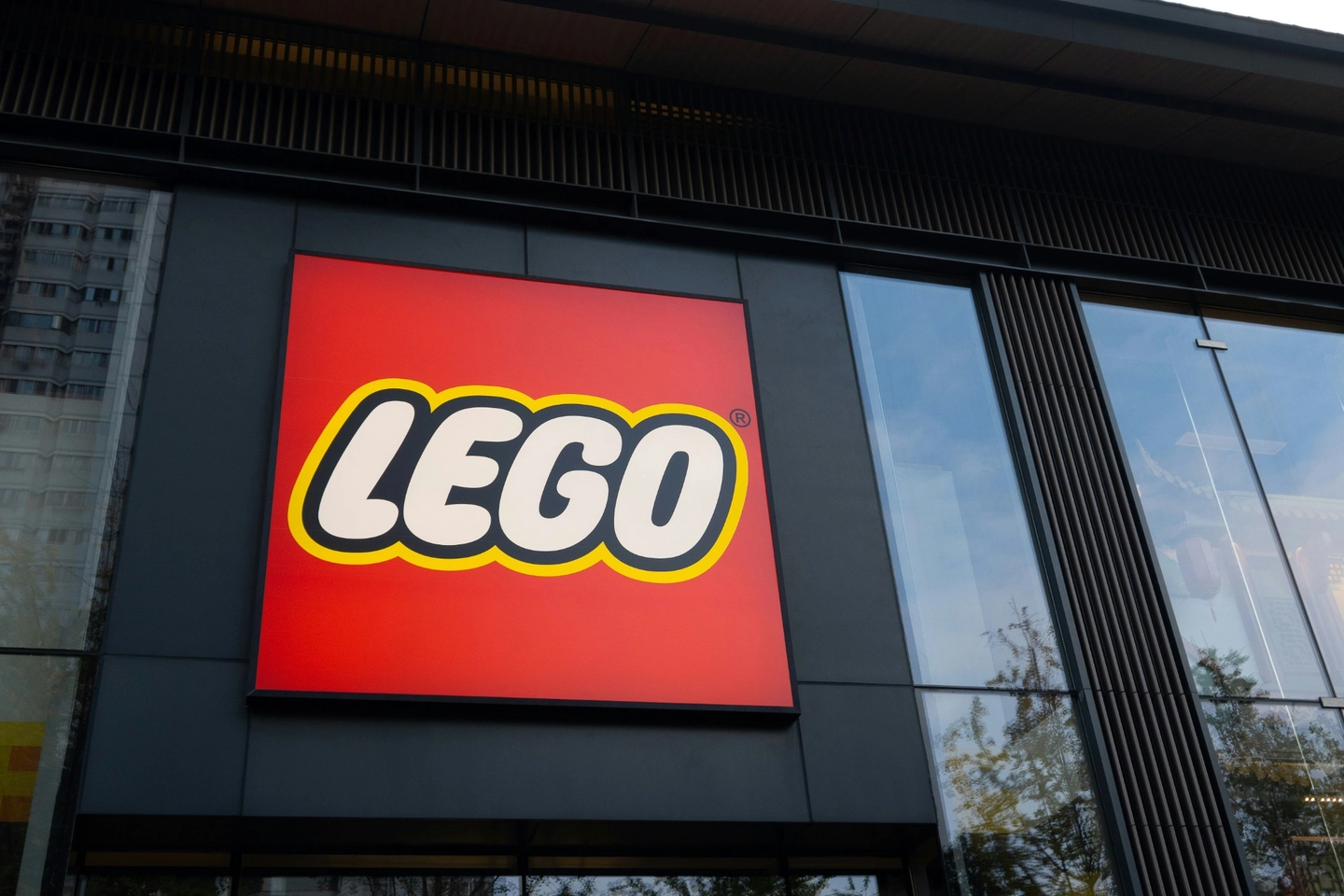 LEGO-logoen på en rød skiltplate utenfor en butikkfasade, sett nedenfra